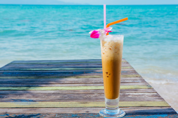 Ice coffee on wooden table with sea background