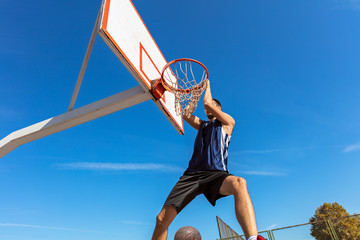 Slam Dunk. Side view of young basketball player making slam dunk