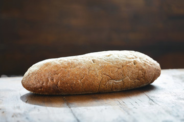 Whole loaf homemade bread wooden table close up