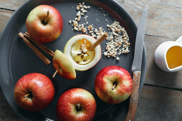 Raw ingredients for cooking baked apples with nuts, honey and cinnamon on wooden table top view