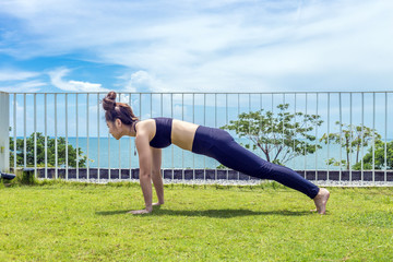 Happy Asian woman wearing black sport wear practice yoga Straight arm Plank on the beach,Feeling relax and comfortable,Healthy Concept