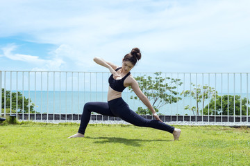 Fototapeta na wymiar Happy Asian woman wearing black sport wear relaxing in yoga High Lunge twist pose with beautiful sea view,Healthy Concept