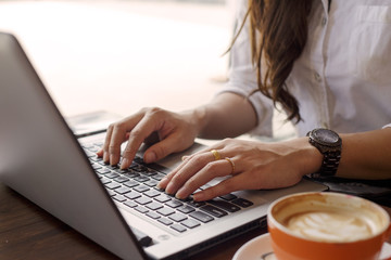 Close up hands of Business woman wearing white shirt working with laptop and coffee cup in coffee shop cafe,Business and Financial concept