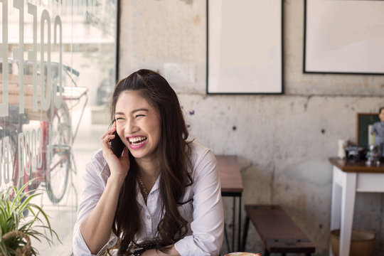 Beautiful young Asian woman Laugh with talking mobile phone in coffee shop cafe,Feeling so happiness and relax