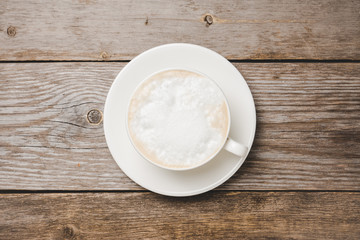 Sweet coffee latte in white cup on the rustic background. Selective focus.