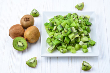Freshly sliced kiwi fruit with whole kiwis in background.