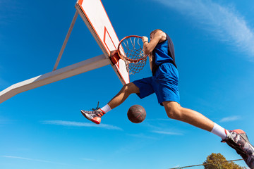 Slam Dunk. Side view of young basketball player making slam dunk