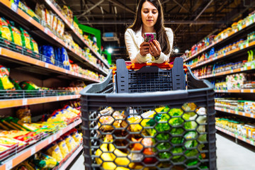 woman with smartphone in store. grocery shopping. gadgets and shopping.