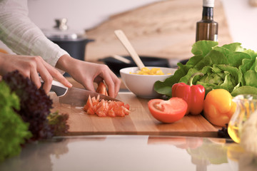 Close Up of human hands cooking vegetable salad in kitchen on the glass table with reflection. Healthy meal, and vegetarian food concept