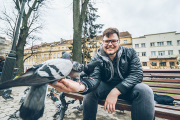 young man feed doves in city park.