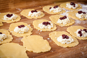 A close-up of the process of making buns from cottage cheese and berries on a wooden table