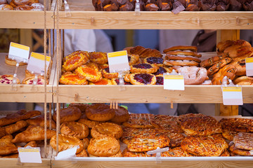 Showcase of a bakery with fresh pastries: pizza, buns with berries and poppy seeds, pie with meat