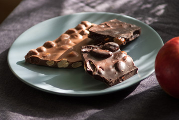 Dark and milk chocolate with nuts and apple on a plate