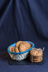 homemade oat cookies with sunflower seeds in and near blue checkered basket on shale board