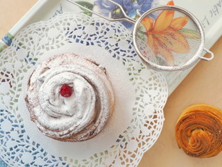 Freshly baked cruffin decorated with sugar powder and dried cranberries. Close up, top view. Selective focus.