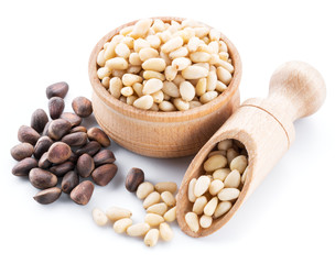 Pine nuts in the wooden bowl on the white background. Organic food.
