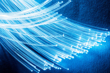 Bundle of optical fibers with lights in the ends. Blue background.