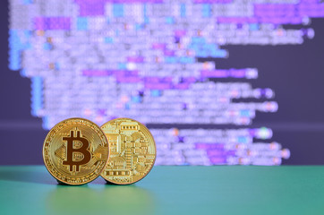 Two gold bitcoins lie on the green surface on the background of the display, which shows the...