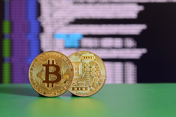 Two gold bitcoins lie on the green surface on the background of the display, which shows the...