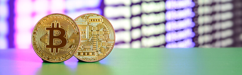Two gold bitcoins lie on the green surface on the background of the display, which shows the...
