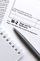 The pen and notebook on the tax form W-2 Wage and Tax Statement. The time to pay taxes