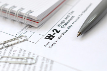 The pen and notebook on the tax form W-2 Wage and Tax Statement. The time to pay taxes