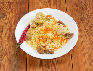 Cooked pilaf on white dish on a rustic table