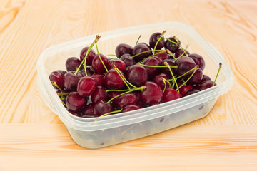 Dark red sweet cherries in plastic container at selective focus