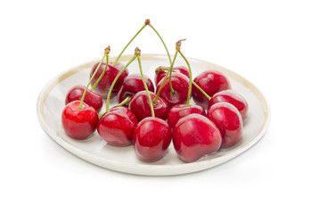 Dark red sweet cherries on saucer on a white background