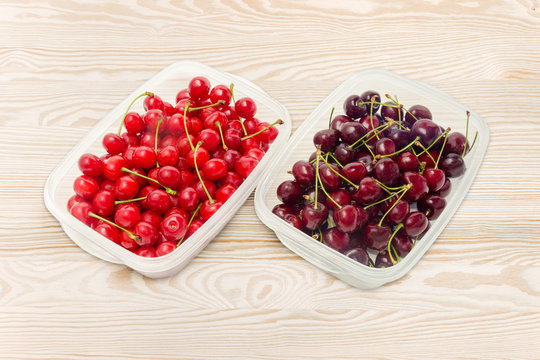 Two varieties of cherries in two different plastic containers