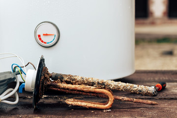 heating element, rust and scale on boiler background, lying on wooden table