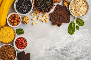 Healthy food nutrition dieting concept. Assortment of high magnesium sources. Banana chocolate spinach, buckwheat, nuts, beans, oat. White background, copy space