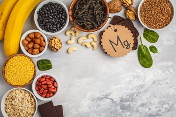 Healthy food nutrition dieting concept. Assortment of high magnesium sources. Banana chocolate spinach, buckwheat, nuts, beans, oat. White background, copy space