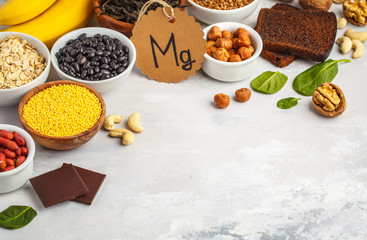 Healthy food nutrition dieting concept. Assortment of high magnesium sources. Banana chocolate spinach, buckwheat, nuts, beans, oat. White background, copy space