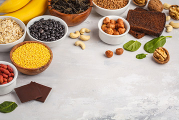 Healthy food nutrition dieting concept. Assortment of high magnesium sources. Banana chocolate spinach, buckwheat, nuts, beans, oat. White background, copy space