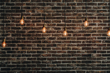 Vintage bulbs hanging on wires an the background of a red brick wall