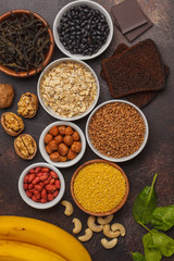 Healthy food nutrition dieting concept. Assortment of high magnesium sources. Banana chocolate spinach, buckwheat, nuts, beans, oat. Dark background
