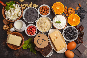 Healthy food nutrition dieting concept. Assortment of high calcium sources. Dairy products, legumes, eggs, nuts, chocolate, poppy, sesame, chocolate. Dark background, top view
