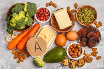 Healthy food nutrition dieting concept. Assortment of high vitamin A sources. Carrots, nuts, broccoli, butter, cheese, avocado, apricots, seeds, eggs. White background, top view - obrazy, fototapety, plakaty