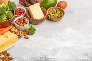 Healthy food nutrition dieting concept. Assortment of high vitamin A sources. Carrots, nuts, broccoli, butter, cheese, avocado, apricots, seeds, eggs. White background, copy space