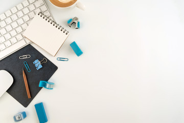 Flat lay, top view office table desk. Workspace with blank note book, keyboard, Blue office supplies and coffee cup on white background.