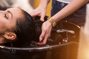 Close up of hands hairdresser washes the client's hair. Spa, care, beauty and people concept