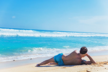 Man lying and enjoying on a sandy tropical beach.