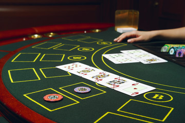 Casino black jack table with chips and cards. Winning combination. Hand of Croupier behind gambling table.