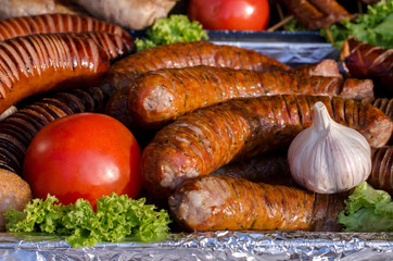 assorted sausages grilled on skewers on a large plate, mushrooms on the grill. Street festival food.