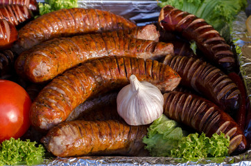 assorted sausages grilled on skewers on a large plate, mushrooms on the grill. Street festival food.