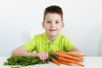 Closeup of adorable young boy with carrot. White background