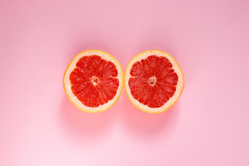 Grapefruit cut in half on a pink background