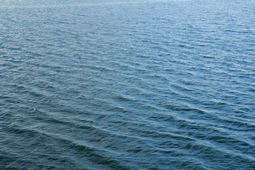 Water surface with ripples and sunrays reflections