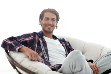 close-up of a smiling guy stroking his dog while sitting in a large armchair.